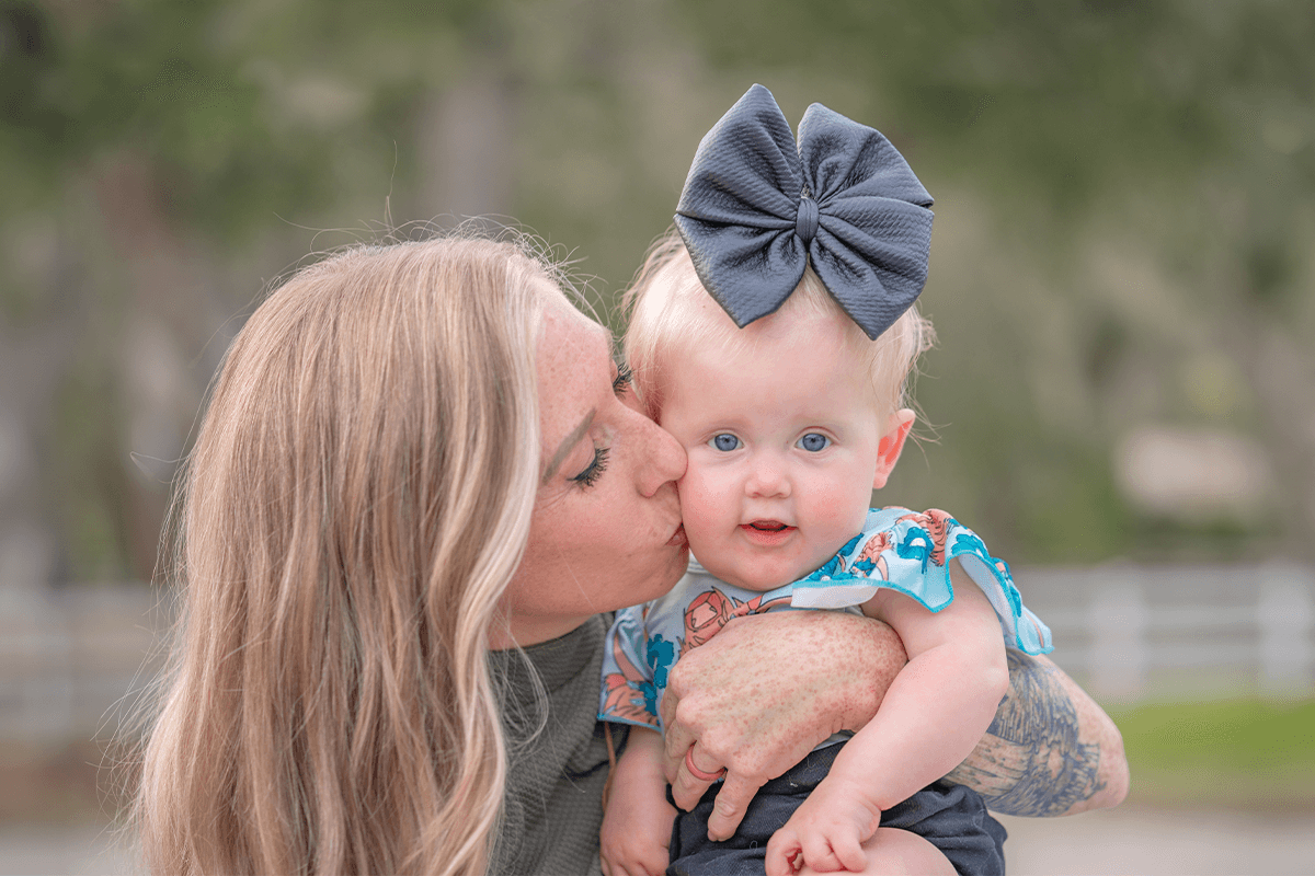 Brianna Mahon holding and kissing her daughter