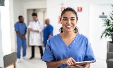 One focused person standing in front of a group of unfocused people smiling while wearing scrubs