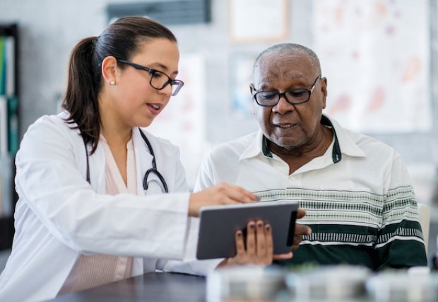 Un médico mostrando los resultados a un paciente en una tableta.