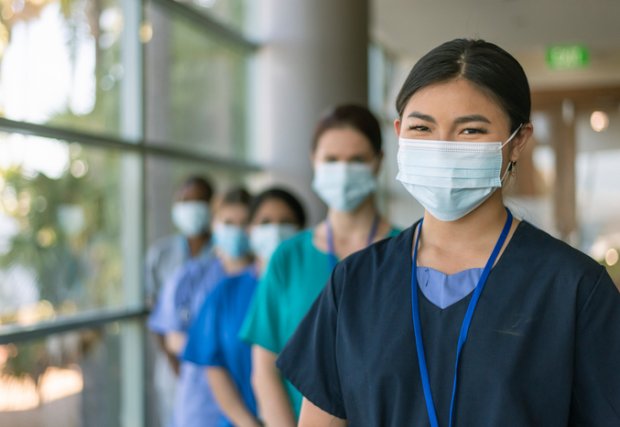 Imagen de archivo de cinco profesionales médicos con máscaras y sonriendo a la cámara