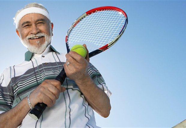 Man outside with a tennis racket and tennis ball