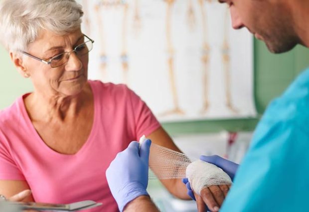 Female patient getting her hand bandaged by doctor