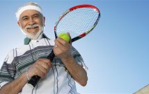 Man outside with a tennis racket and tennis ball