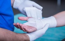 A medical personnel wrapping someone's wrist wound.